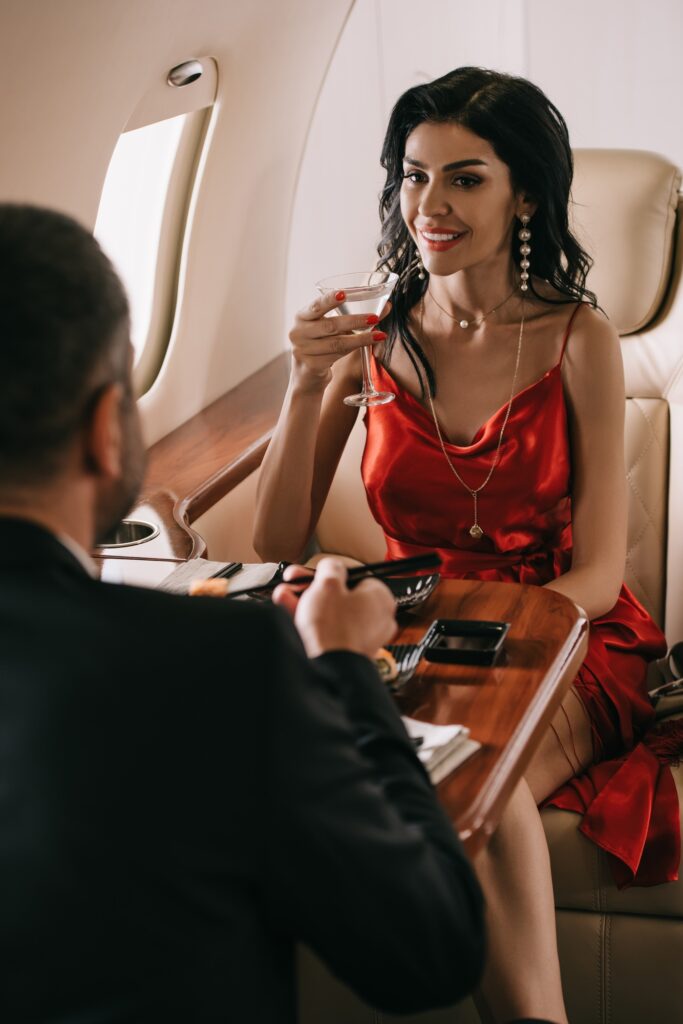 selective focus of elegant woman in red dress holding martini glass and looking at man in private