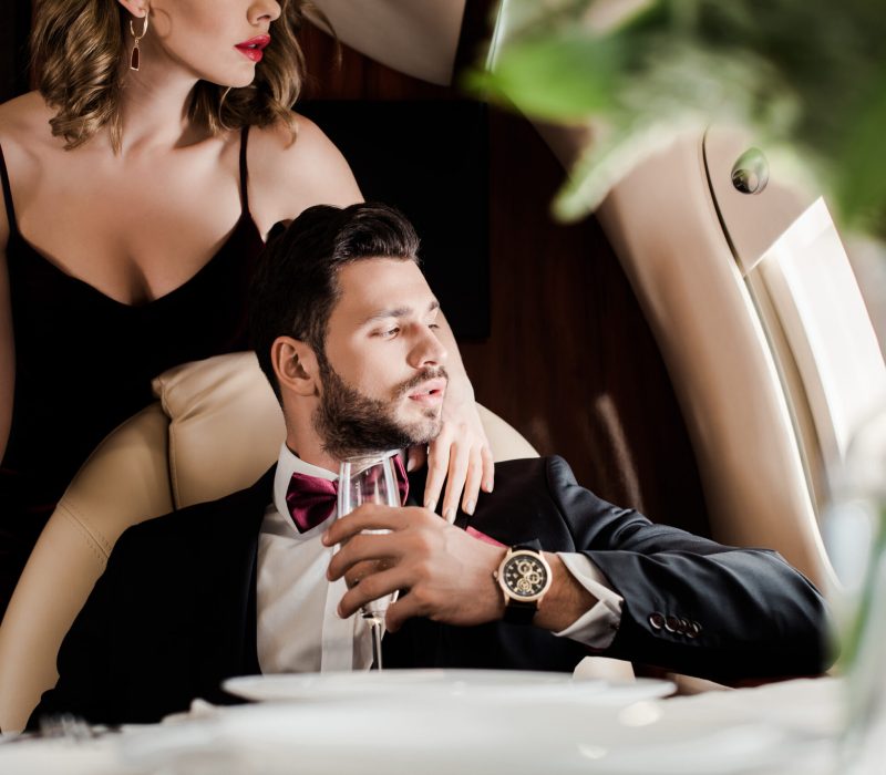 cropped view of sexy woman touching elegant man holding glass of champagne in plane cropped view of sexy woman touching elegant man holding glass of champagne in plane